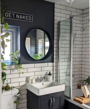 丸い鏡と壁の看板を備えた黒いバスルーム