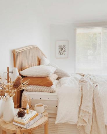 Accogliente camera da letto minimale con toni zucca e cuscini di cotone a strati sul letto