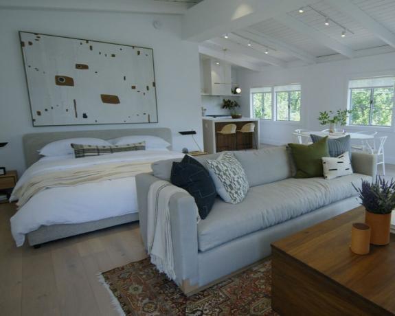 spazio abitativo con schema neutro con letto, divano e opere d'arte