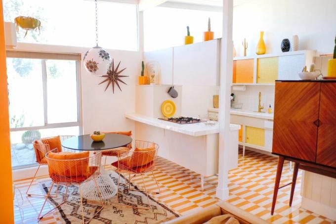 Oranžinės ir baltos tiesios plytelės atviro plano virtuvės ir valgomojo erdvėje su retro ryškiais bruožais
