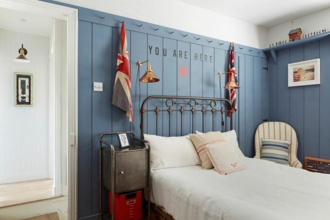Schlafzimmer mit Eisenbettrahmen und blau getäfeltem Zimmer