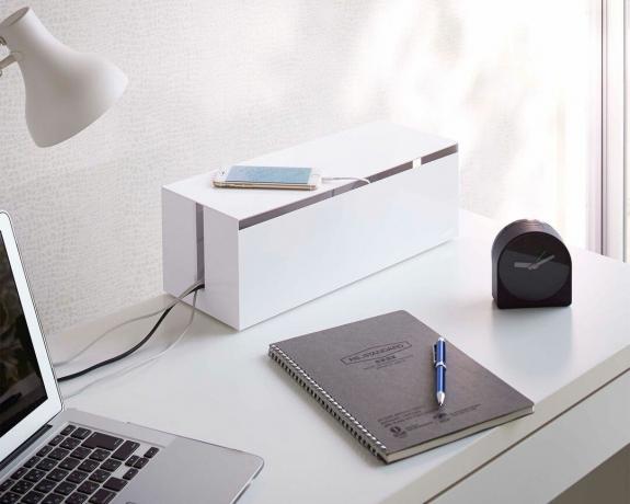 Hvit kabelhåndteringsboks på hvitt skrivebord