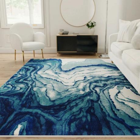 Ivy Bronx Omari Power Loom Ocean Blue kilimėlis svetainėje su balta sofa