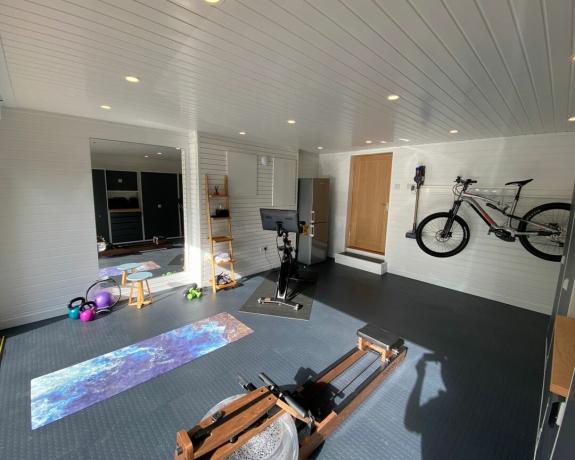 Гаражна домашна фитнес зала с постелки за йога и велосипед на стена