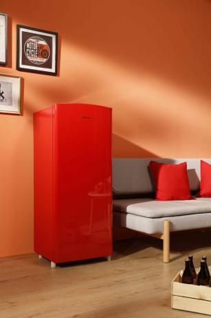 un frigider roșu aprins într-un living vibrant, cu o canapea gri și podea din lemn
