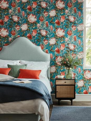 Papel pintado de dormitorio con características brillantes y cama tapizada con telas de color azul claro y brillantes