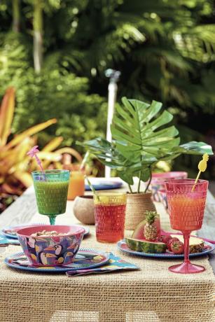verrerie colorée et bols et assiettes botaniques à l'extérieur dans un jardin
