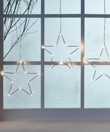 decoración navideña de ventanas con estrellas iluminadas colgando de los cristales