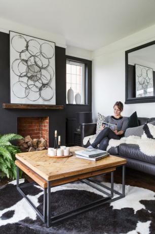 غرفة معيشة أحادية اللون مع طاولة قهوة خشبية كبيرة وسجادة من جلد البقر وأريكة جلدية