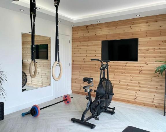domowa siłownia z drewnianą podłogą, telewizorem i panelami ściennymi - Sophie McNally