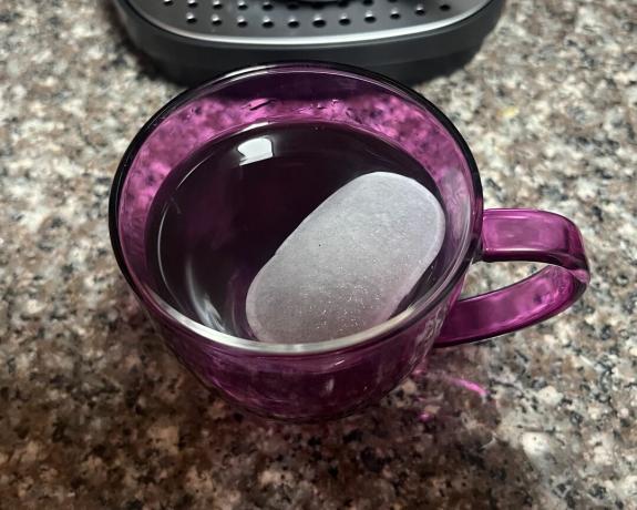 En kop kaffe i lilla krus med en isterning faldt i