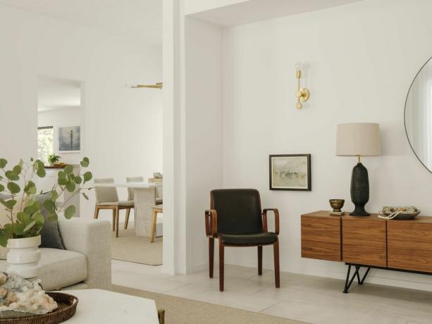 dnevna soba z modernim pohištvom iz sredine stoletja, bele stene, kamnita tla, pogled v jedilnico