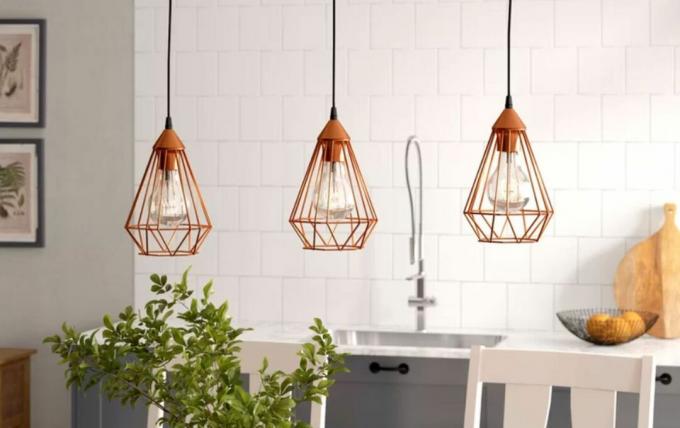 3 lampade a sospensione a gabbia arancioni su un'isola della cucina