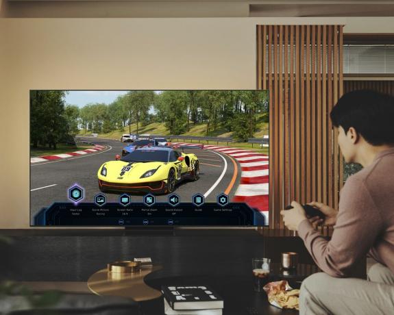 Odrasel moški igra igro avtomobilskih dirk na konzoli in Samsungovem The Frame TV