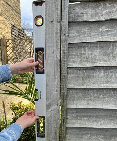 Osoba koja koristi libelu za mjerenje ograde u dvorištu