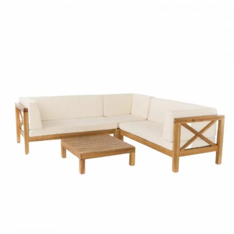 Um sofá de canto ao ar livre com almofadas brancas e uma mesa
