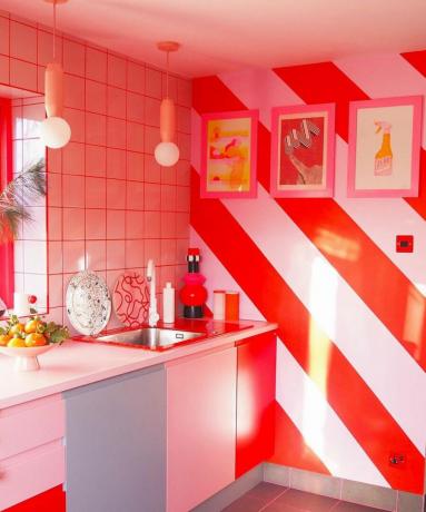 Roze en rode keuken met wanddecoratie met snoepstrepen en ingelijste kunst aan de muur