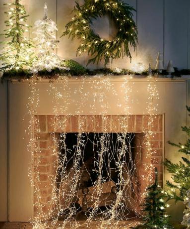 تصميم مدفأة عيد الميلاد مع أضواء النجوم المتتالية وأوراق الشجر دائمة الخضرة