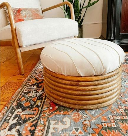 Gotowy podnóżek tapicerowany kremową tkaniną zastawiony w salonie