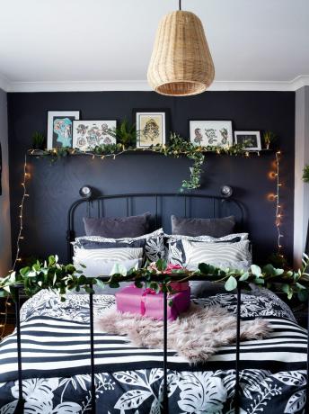 Camera da letto grigio scuro con letto in ferro e decorata per natale con finta vegetazione