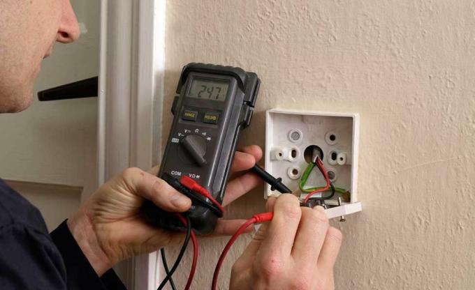 Bir dönem ev tadilatını yeniden kablolarken bir elektrikçi prizleri test ediyor