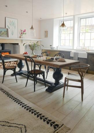 黒い椅子、薪ストーブ、敷物、床板のある素朴なダイニングルーム