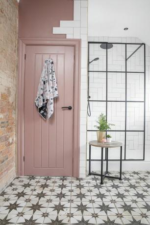 Bad med mønstret flisgulv, dusjvegg i Crittal-stil, hvite metrofliser og rosa vegg- og dørmaling