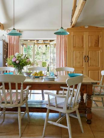 sala de jantar de casa de fazenda com mesas e cadeiras rústicas e teto com vigas