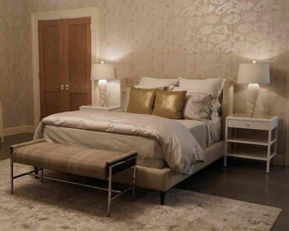 Dormitorio neutro con almohadas doradas sobre una cama blanca