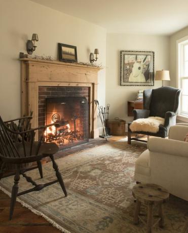 Sala de estar con fuego encendido en 1700 casa de campo de Nueva Inglaterra