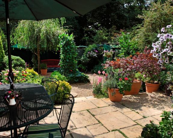 Ein Garten mit Terrasse, Sonnenschirm und Kübelpflanzen in London, Großbritannien