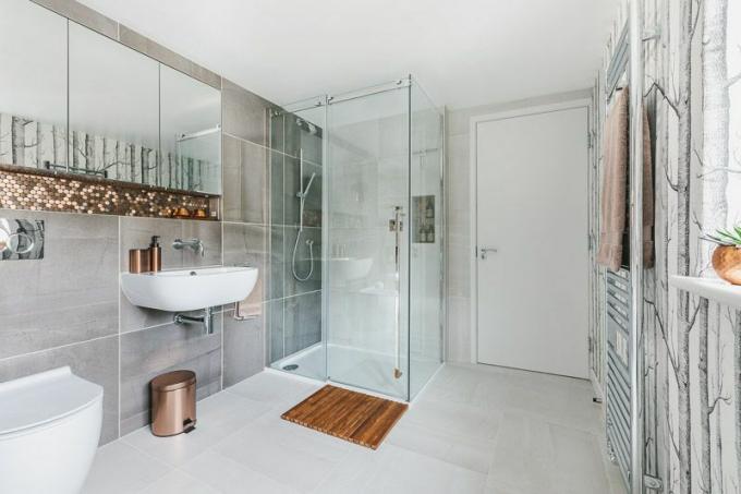 baie cu gresie gri, duș modern, accente de cupru și tapet cu modele