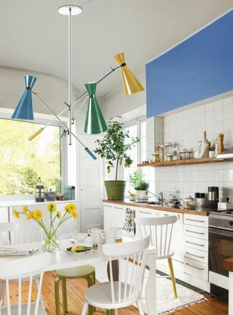 ห้องครัวพร้อมชุดครัวสีขาวและตู้ทาสีฟ้าพร้อมไฟประดับตกแต่งโดย Delight full
