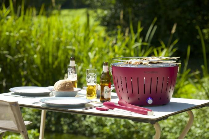 En Lotus Grill Smokeless BBQ fra Cuckooland på et utendørs bord med grillverktøy og øl