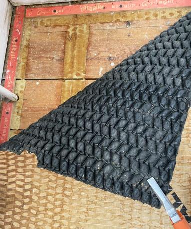 шматок килимової підкладки знімається плоскогубцями, щоб відкрити дошки підлоги