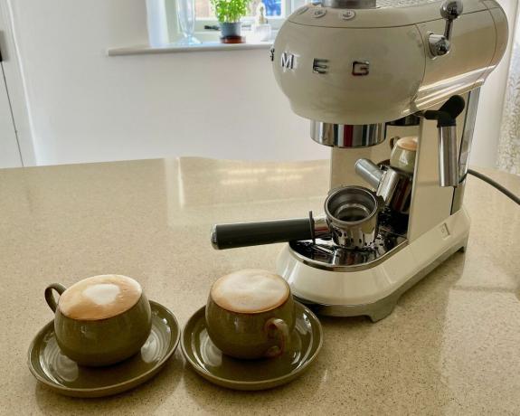 Smeg espressomaskin i hvitt på kjøkkenbenk med to krus kaffe