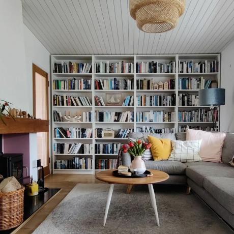 Uma sala de estar com uma parede de estantes, um sofá e uma mesa de centro