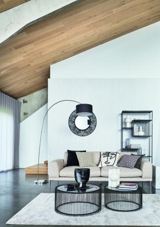 ruang tamu putih dengan lantai abu-abu, meja kopi modern dan unit rak yang serasi, lampu lantai hitam, cermin hitam, sofa krem