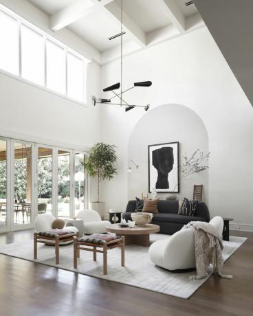 sala de estar blanca con techo abovedado, esquema monocromático, pisos de madera, espacio al aire libre a través de las puertas, muebles modernos, luz colgante negra
