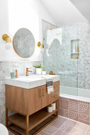 bagno e doccia con piastrelle esagonali grigie, piastrelle rosa, accessori in ottone, vanità