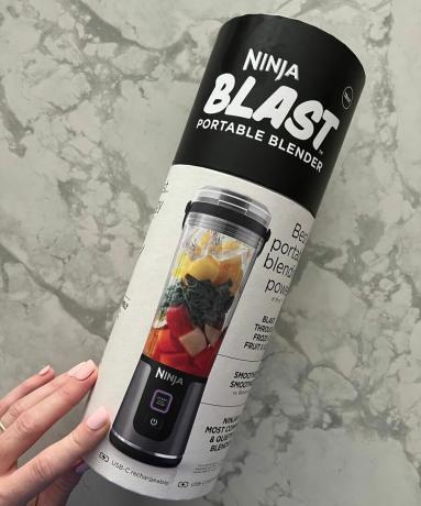 Confezione cilindrica del frullatore portatile Ninja Blast su piano di lavoro in marmo tenuto da Heather Bien