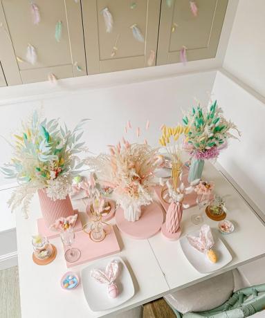 Csinos, modern pasztell asztali stílus, színes szárított virágokkal töltött pasztell vázákkal és aranyos nyuszifüles teríték ötlettel.