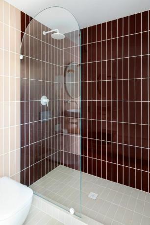 Fioletowe i jasnobeżowe pionowe płytki prysznicowe poza szklanymi drzwiami prysznicowymi