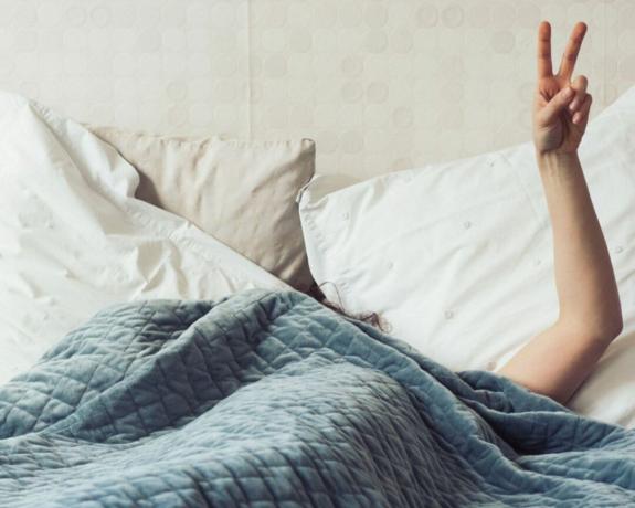 kako oprati dekicu s utezima - žena u krevetu s utegom deke znak mira - mela
