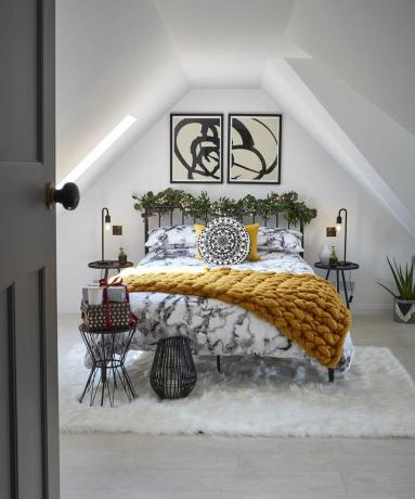 ein Loft-Schlafzimmer mit symmetrischen Dachvorsprüngen, Kunstwerken und Nachttischbeleuchtung – Malcolm Menzies