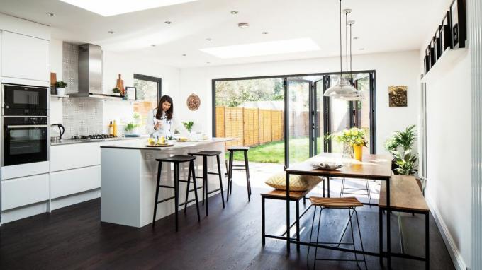 Ide ekstensi murah: ekstensi dapur berwarna putih dengan tempat duduk dan meja makan bergaya industri