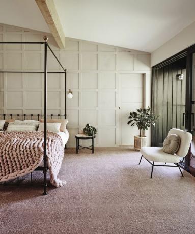 Um quarto grande com cama de dossel e carpete rosa