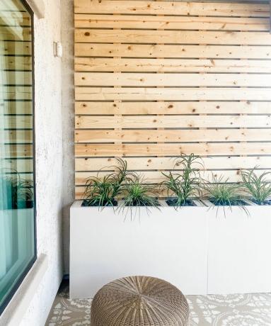 Eine dekorativ geflieste Terrasse mit Holzpalettenbrettern und Pflanzen im Freien