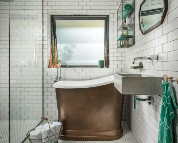 Uma pequena casa de banho de azulejos com duche e banheira com acabamento em cobre