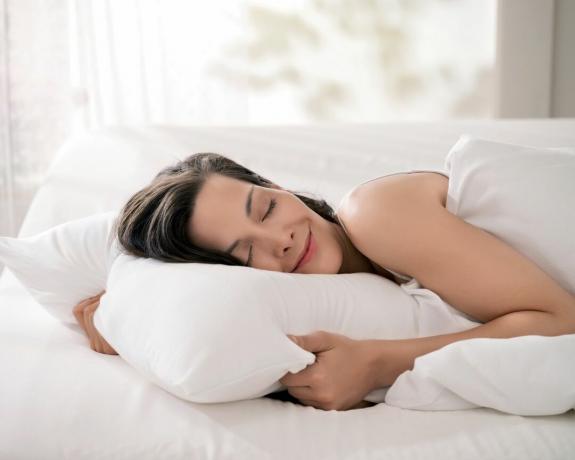 moteris lovoje apsikabinusi baltą pagalvę – tempur